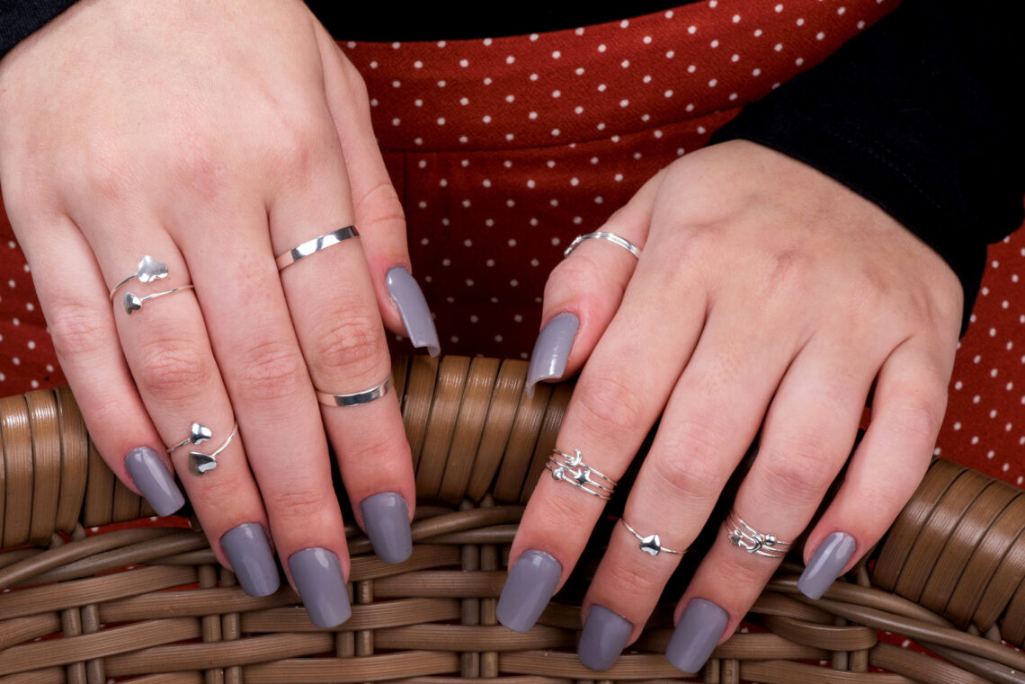 Mãos femininas com diversos anéis falange em prata nos dedos.