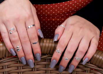 Mãos femininas com diversos anéis falange em prata nos dedos.