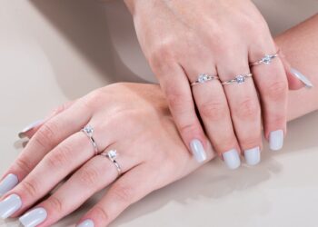 Mãos femininas utilizando diversas peças de anel solitário em seus dedos anelar, médio e indicador.